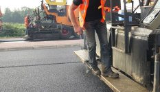Met een asfaltmachine wordt nieuw asfalt aangebracht op een provinciale weg.