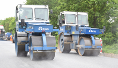 Twee walsmachines van aannemer KWS die naast elkaar over het net aangebrachte asfalt rijden