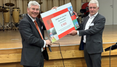 Gedeputeerde Van Schie reikt cheque uit aan wethouder Van der Schoor van Renwoude met de opbrengst van de spaarpaal die op de Dorpsstraat heeft gestaan