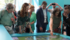 Gedeputeerde Van Muilekom bij interactieve tafel met info over de Hollandse Waterlinie en de Limes