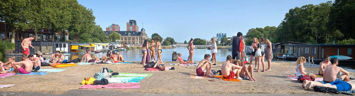 Jongeren in zwemkleding vermaken zich op een zonnige dag bij een kanaal in Utrecht
