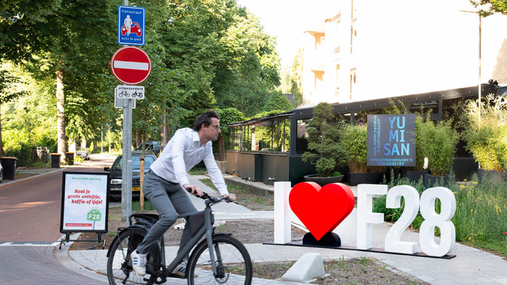 Man op elektrische fiets onderweg naar werk rijdend langs grote ‘I love F28’ letters.