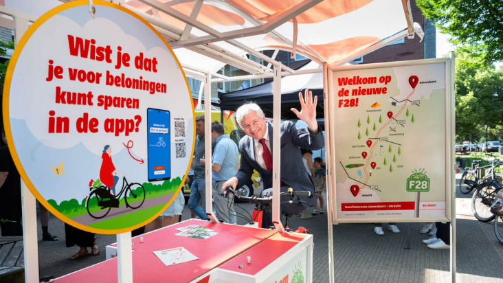 Gedeputeerde bij marktkraampje met info over fietsapp en doorfietsroutes