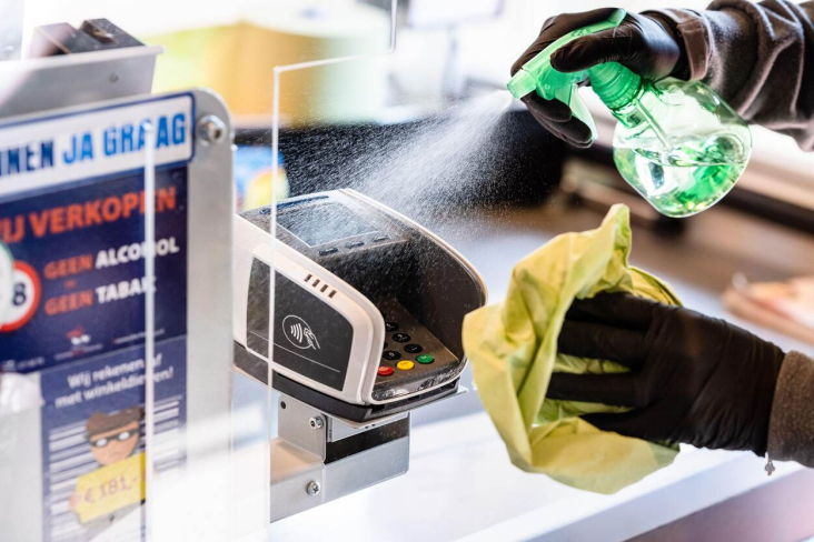 medewerker desinfecteert pinapparaat winkel