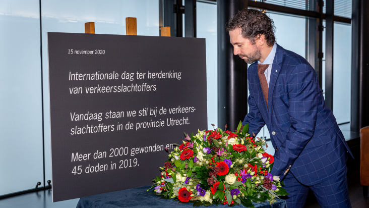 Gedeputeerde Arne Schaddelee legt een bloemstuk bij het bord ter herdenking van de verkeersslachtoffers in de provincie Utrecht in 2019.