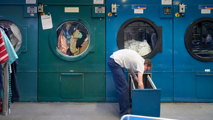 Wasserijmedewerker stop wasgoed in machine