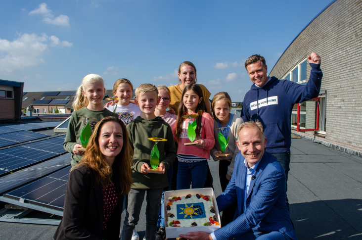 Gedeputeerde Huib van Essen en leerlingen van basisschool de Vlinder vieren de plaatsing van zonnepanelen op deze school d