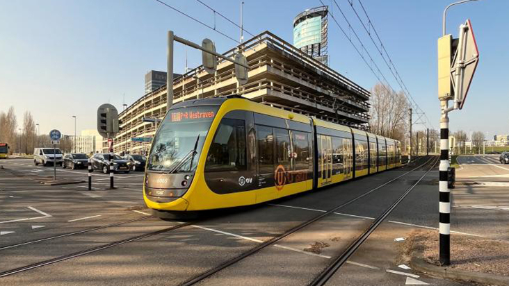 Tram rijdt langs parkeergarage