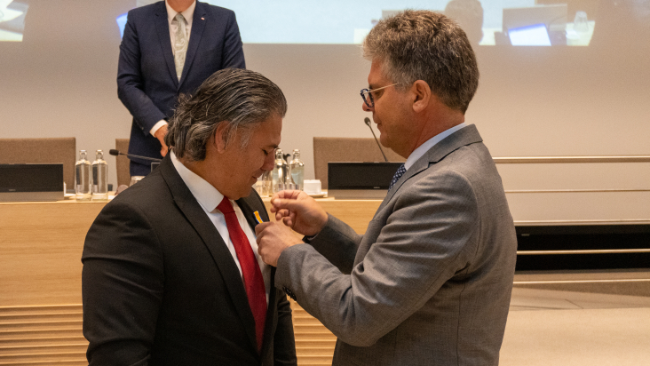 Osman Suna krijgt koninklijke onderscheiding van commissaris van de Koning Hans Oosters opgespeld