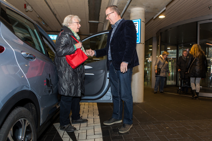 oudere mevrouw wordt geholpen bij uitstappen regiotaxi