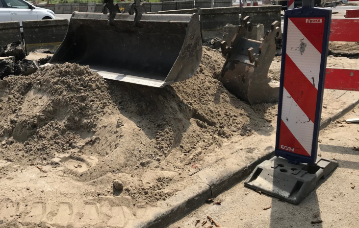 Een graafmachine die zand langs een weg verplaatst