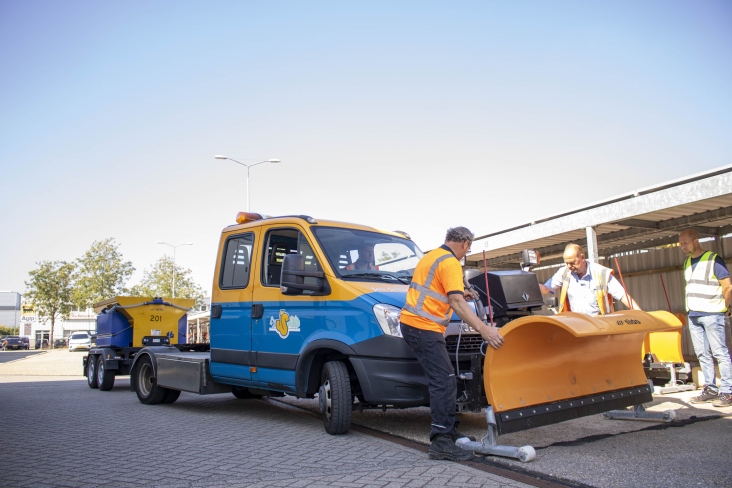 Aannemer zet sneeuwschuiver op de strooiwagen