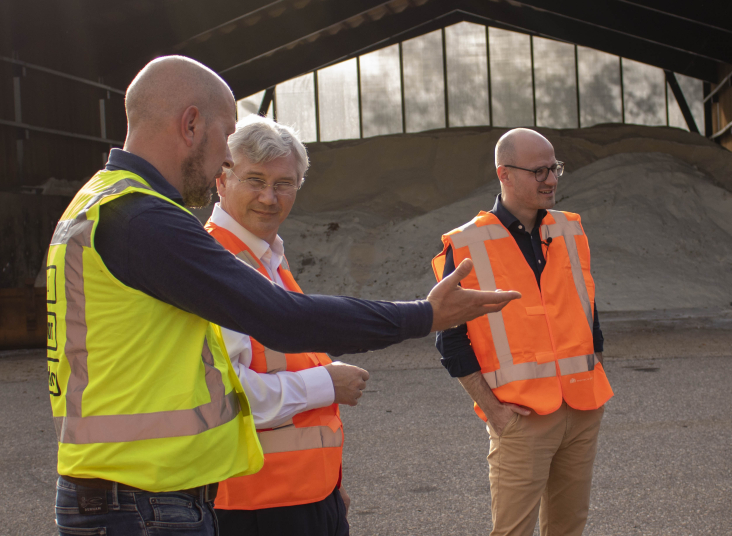 Gedeputeerden Andre van Schie en Has Bakker samen met een vertegenwoordiger van Aebi-Schmidt bij de strooiwagen