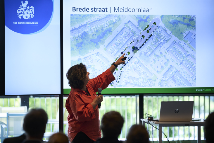 Een van de prentatoren wijst iets aan op een scherm tijdens een presentatie op congres klimaatadaptatie