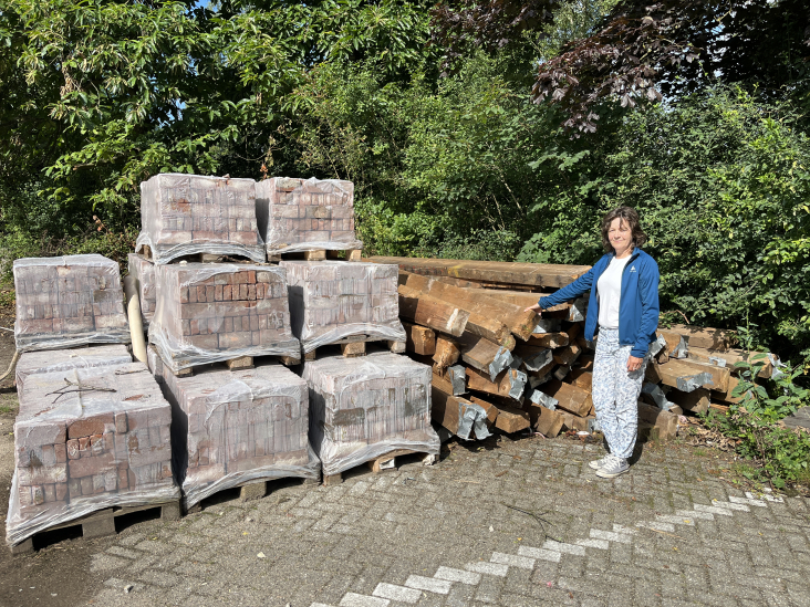 Projectleider Joke Kleijweg bij de verpakte bakstenen op pallets en houten balken.