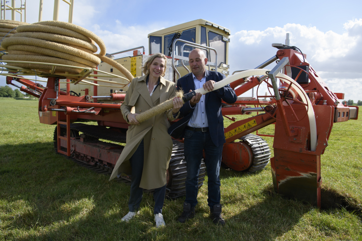 Gedeputeerde Mirjam Sterk van de provincie Utrecht en Arjan van Rijn, bestuurder van waterschap Amstel Gooi en Vecht, koppelen eerste stuk waterinfiltratiesysteem op weiland in Waardassackerpolder