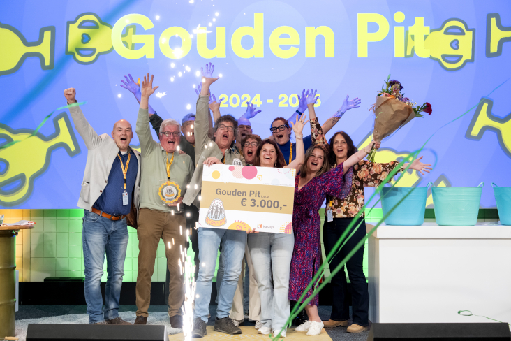 Deelnemers van kern met pit die enthousiast poseren met hun prijs op een podium