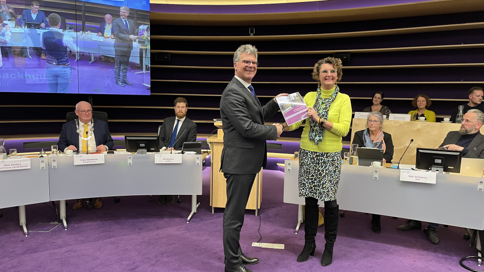 Een raadslid van de gemeente Nieuwegein overhandigt de profielschets voor de nieuwe burgemeester aan commissaris van de koning Hans Oosters