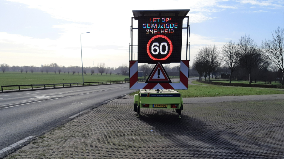 Een tekstkar langs de N402 in Loenen met daarop vermeld dat de nieuwe maximumsnelheid 60 km/uur is.