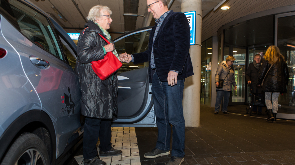 oudere mevrouw wordt geholpen bij uitstappen regiotaxi