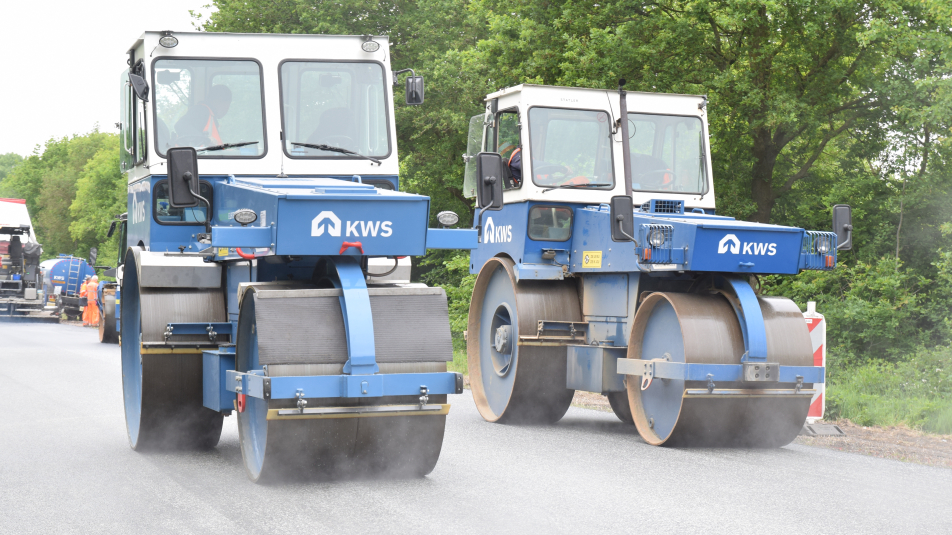 Twee walsmachines van aannemer KWS die naast elkaar over het net aangebrachte asfalt rijden