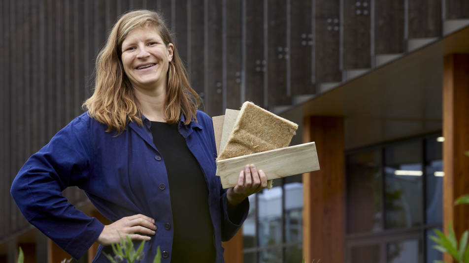 Nienke Binnendijk met biobased materiaal en biobased huis op achtergrond.5jpg