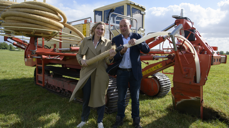 Gedeputeerde Mirjam Sterk van de provincie Utrecht en Arjan van Rijn, bestuurder van waterschap Amstel Gooi en Vecht, koppelen eerste stuk waterinfiltratiesysteem op weiland in Waardassackerpolder