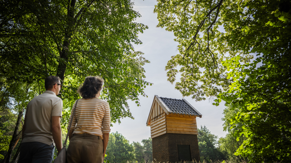 Twee bezoekers kijken naar een hutje op Kamp van Zeist